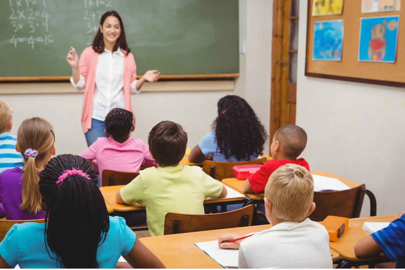 A group of children sitting on the floor in front of a teacher